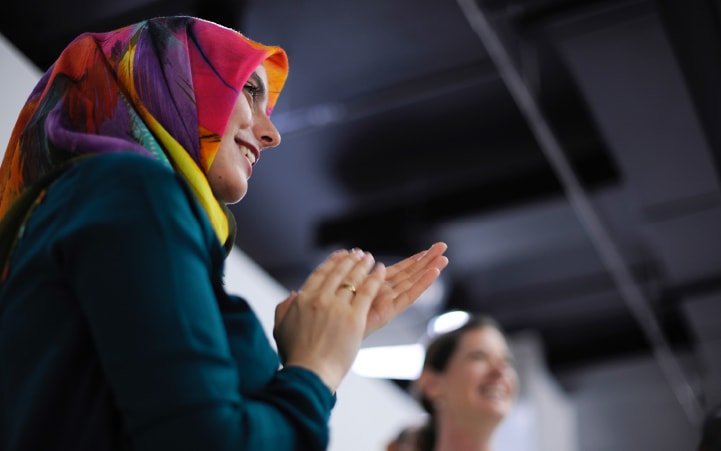 Women wearing head scarf clapping